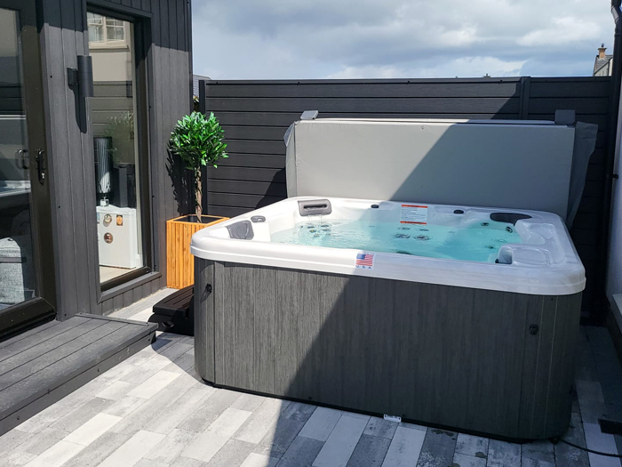 image of an artesian hawaii hot tub installed and filled on a patio