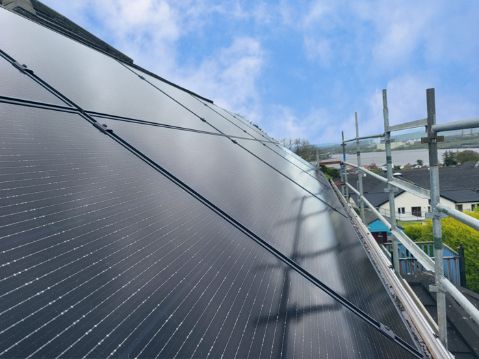 image of solar panels on a roof agaisnt a blue sky with scaffolding