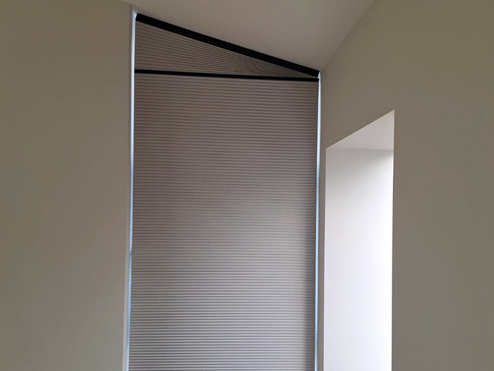 shaped motorised cellular blind with black hardware and grey fabric
