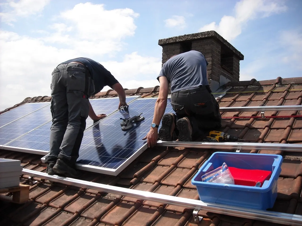 image of two roofers installing solar panels on to mounting rail